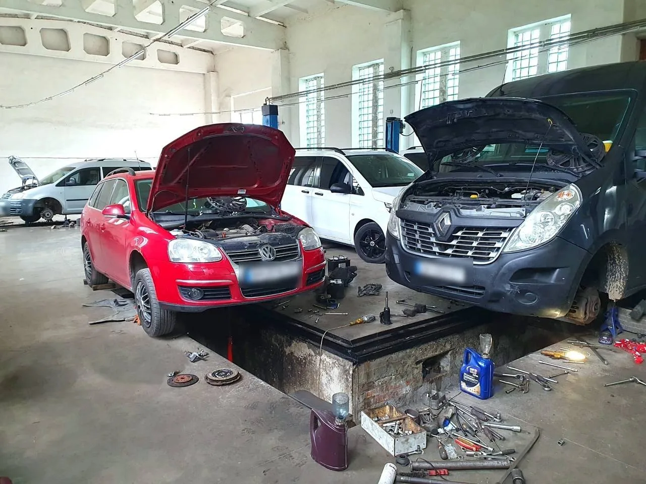 Легковий автомобіль та мікроавтобус над оглядовою ямою в ремонтній зоні майстерні